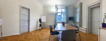 Leerer Besprechungsraum mit einem Konferenztisch und mehreren Stühlen.